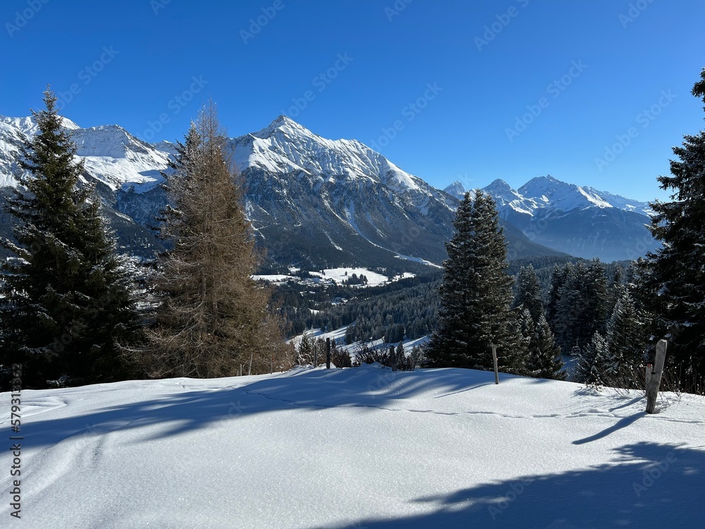 Beautiful sunlit and snow-capped alpine peaks above the Swiss tourist sports-recreational winter resorts of Valbella and Lenzerheide in the Swiss Alps - Canton of Grisons, Switzerland (Schweiz)