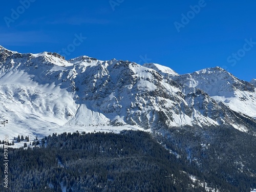 Beautiful sunlit and snow-capped alpine peaks above the Swiss tourist sports-recreational winter resorts of Valbella and Lenzerheide in the Swiss Alps - Canton of Grisons, Switzerland (Schweiz)