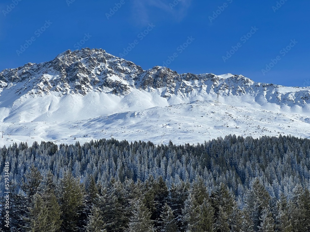 Beautiful sunlit and snow-capped alpine peaks above the Swiss tourist sports-recreational winter resorts of Valbella and Lenzerheide in the Swiss Alps - Canton of Grisons, Switzerland (Schweiz)