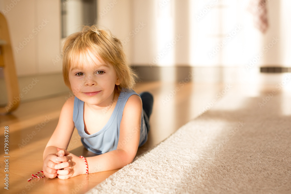 Cute blond toddler child, playing with big toy car