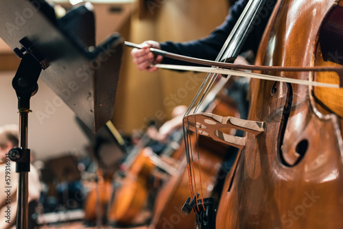 A musician playing the double bass with a bow in an orchestra during a rehearsal