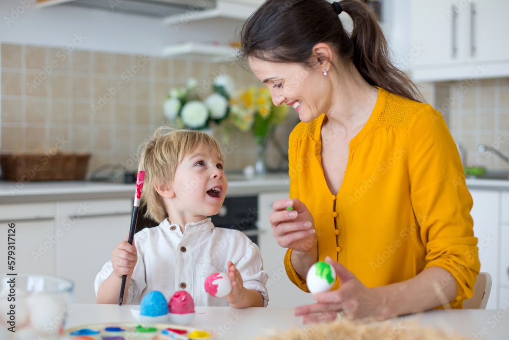 Beautiful blond child, toddler boy, painting easter eggs with mother at home, making easter wreath Beautiful blond child, toddler boy, painting easter eggs with mother at home, making easter wreath
