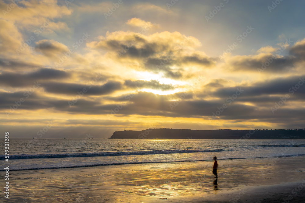 Boy walking on Coronado beach at sunset, San Diego, California