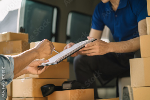 Male appending signature sign on paper for sending boxes with delivery man, Asian man signed with an paper signature on the box, Concept of parcel delivery.