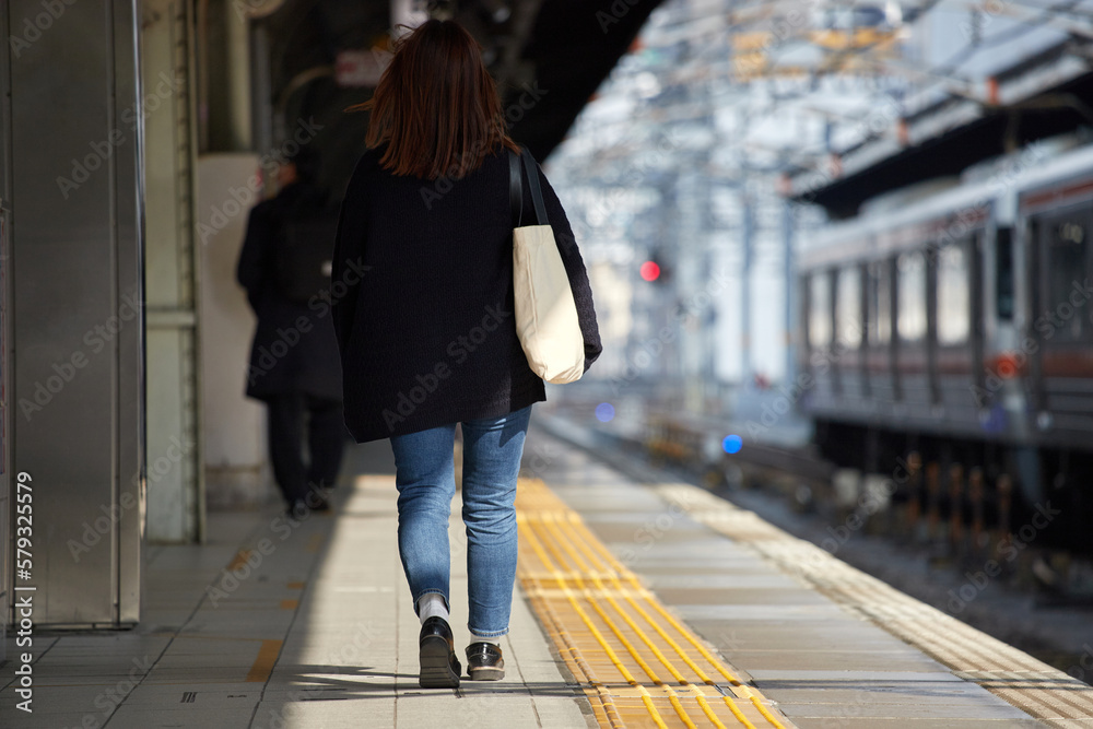 冬の駅のホームで歩く若い女性の後ろ姿