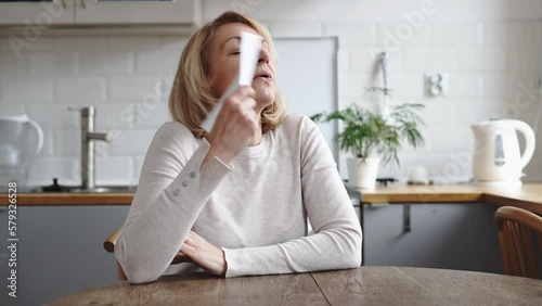 Mature woman sitting at home and having hot flush. Hormone imbalance, menopause concept  photo