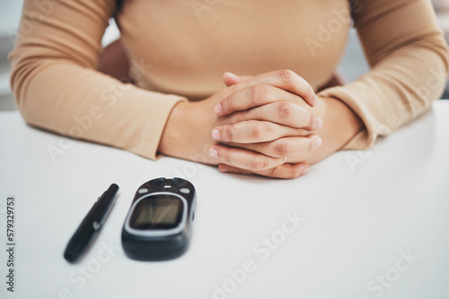 Hands  diabetes and glucose machine on table for woman with medical problem  self care or wellness. Monitor  glucometer or blood test of sugar level  healthcare or insulin for patient at desk in home
