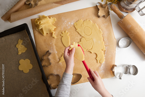 Children's hands cut out a shape for Easter cookies on rolled out dough in a spring decor