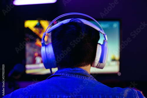 Gamer wearing headphones, live streaming his gameplay for his online subscribers