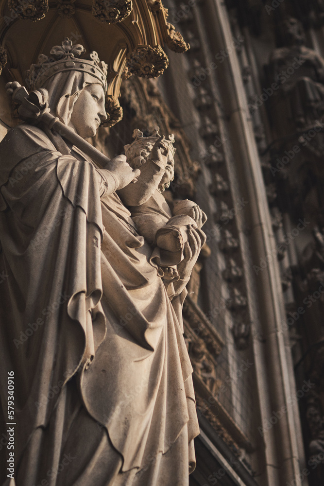 Vertical shot of the Virgin of Paris sculpture and the facade of the Cologne Cathedral, Germany