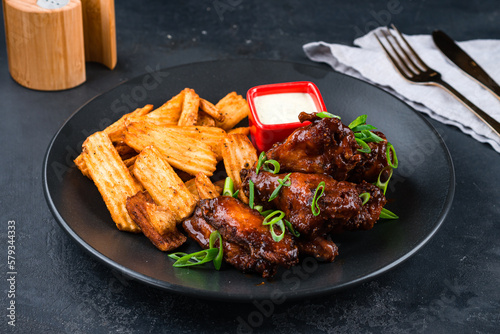 Fried chicken wings with potato chips, green onions and sauce.