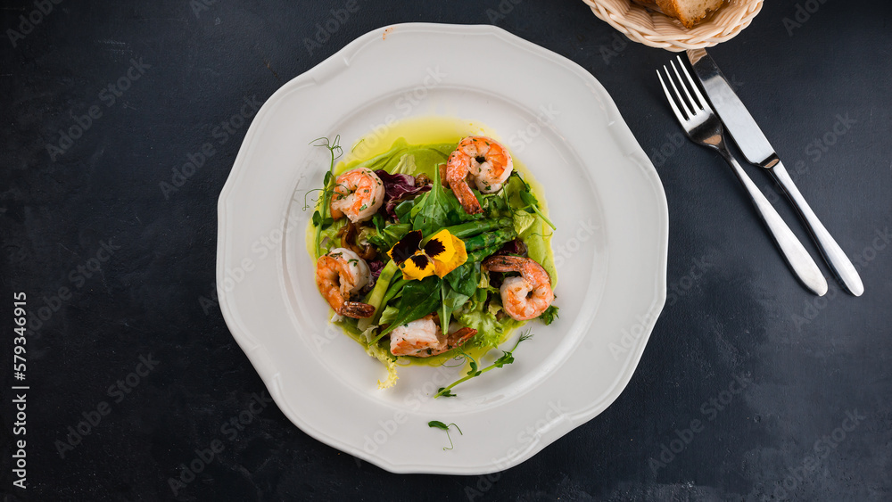 Fresh salad with shrimps, asparagus, lettuce and green sauce.