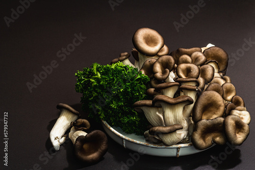 Delicious organic oyster mushrooms with fresh parsley. Source of beta glucan, black stone background