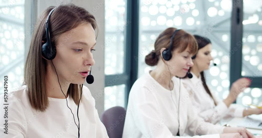 Portrait of attractive successful focused caucasian women working at modern call center office as customer support representatives. Professional female workers using headphones and laptop online.