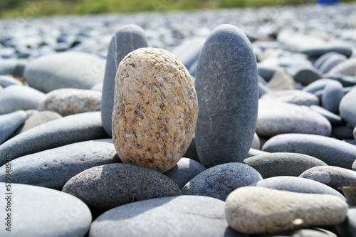 Three oval pebbles on a stony beach.