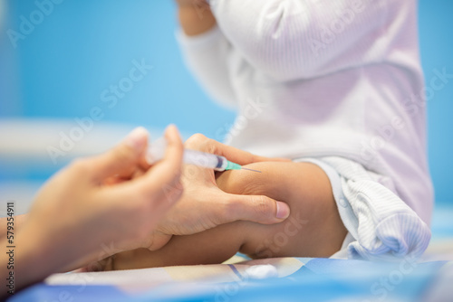 pediatrician Hand hold vaccine liquid injection in syringe for injecting child baby infant. small syringe needle for infant prevention flu by vaccination immunity in Pediatrics hospital clinic.