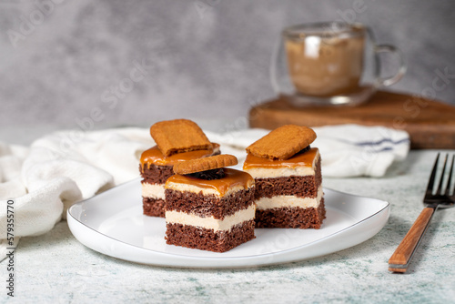 Small dessert cakes. Caramel petit four on a white plates in dark background. Biscuit french petit four cake