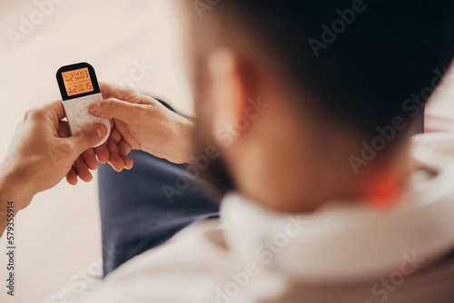 Man use remote control for the neck massager device