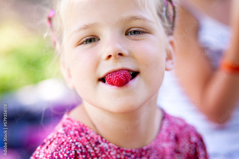 close-up child with raspberries in his mouth. Summer games with children. Healthy food. Summer vitamins. Family holiday close-up child with raspberries in his mouth. Summer games with children. Healthy food. Summer vitamins. Family holiday