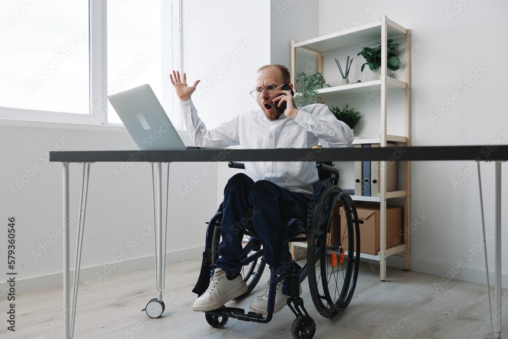 A man in a wheelchair a businessman with tattoos in the office works, talking on the phone, anger and aggression, integration into society, the concept of working a person with disabilities