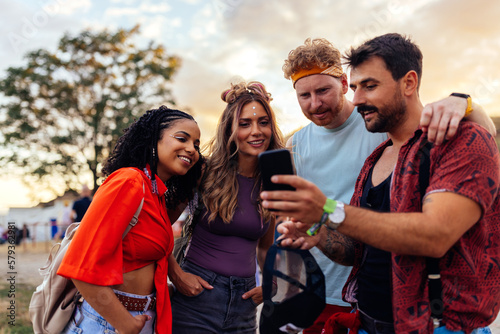 Obraz na plátně Friends using cellphone at music festival