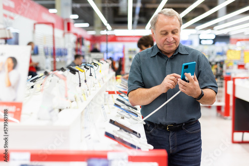 Elderly man chooses mobile phone in store