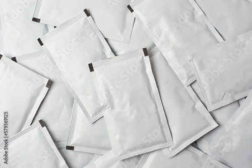 pile of blank white sachet packets full frame background, close-up of scattered food or medicine drug packaging mock-up template 