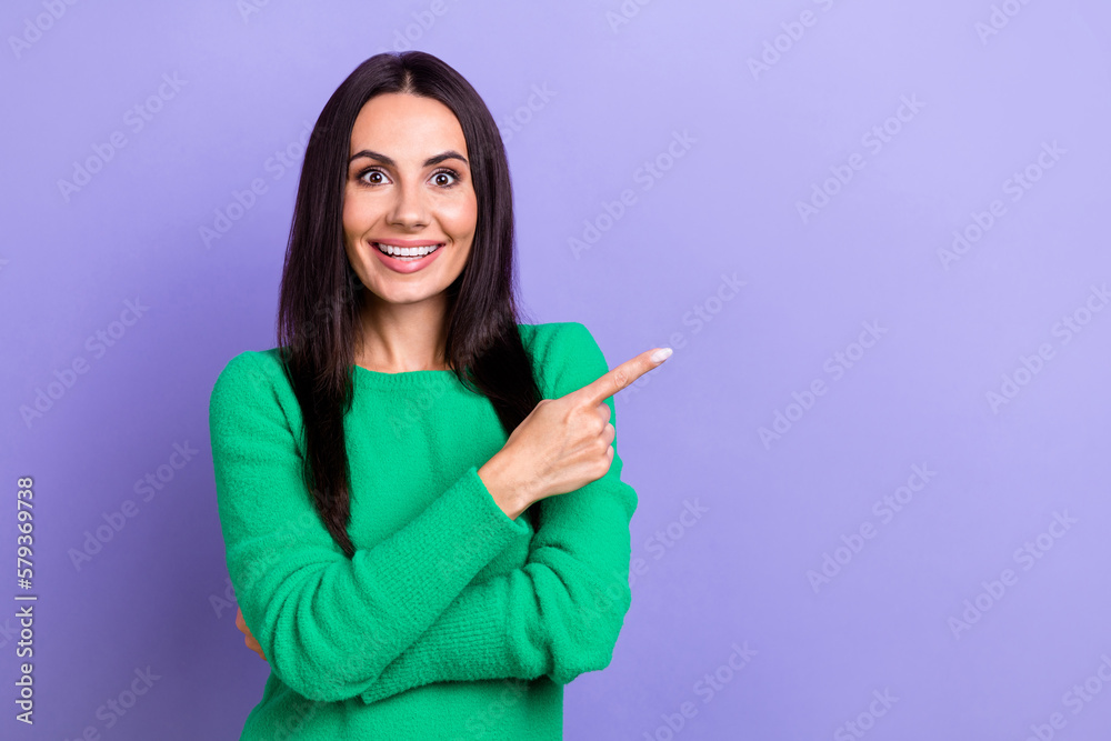 Portrait photo of excited funny hispanic lady wear green pullover direct finger empty space promo banner isolated on violet color background Portrait photo of excited funny hispanic lady wear green pullover direct finger empty space promo banner isolated on violet color background