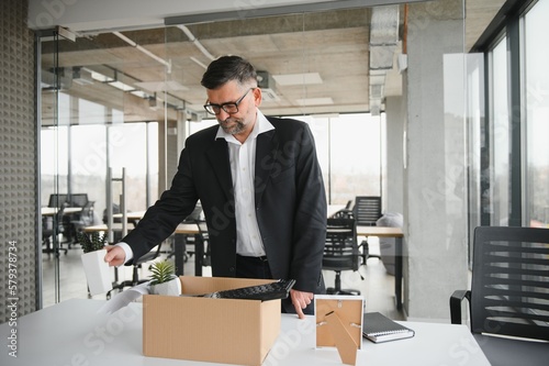 old employee leaving office with the box full of belongings photo