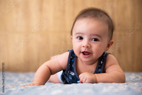 baby lying on a bed, looking forward and smiling. photo