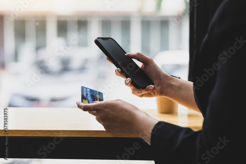 Woman using smartphone and credit card in cafe. Concept of online payment via mobile phone.