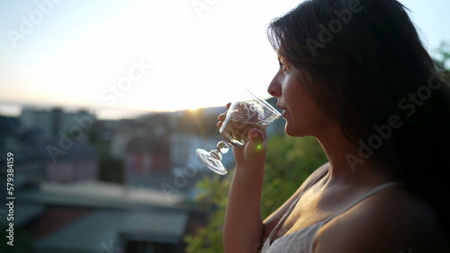 Woman drinking white wine outside during sunset time. Female person enjoying alcoholic beverage during summer day outdoors looking at scenic view