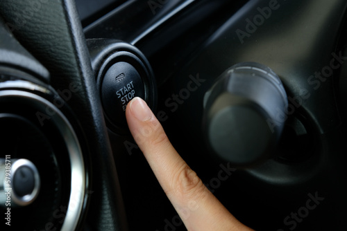 Woman starts the car engine with start-stop button. Modern car interior © Sucharat