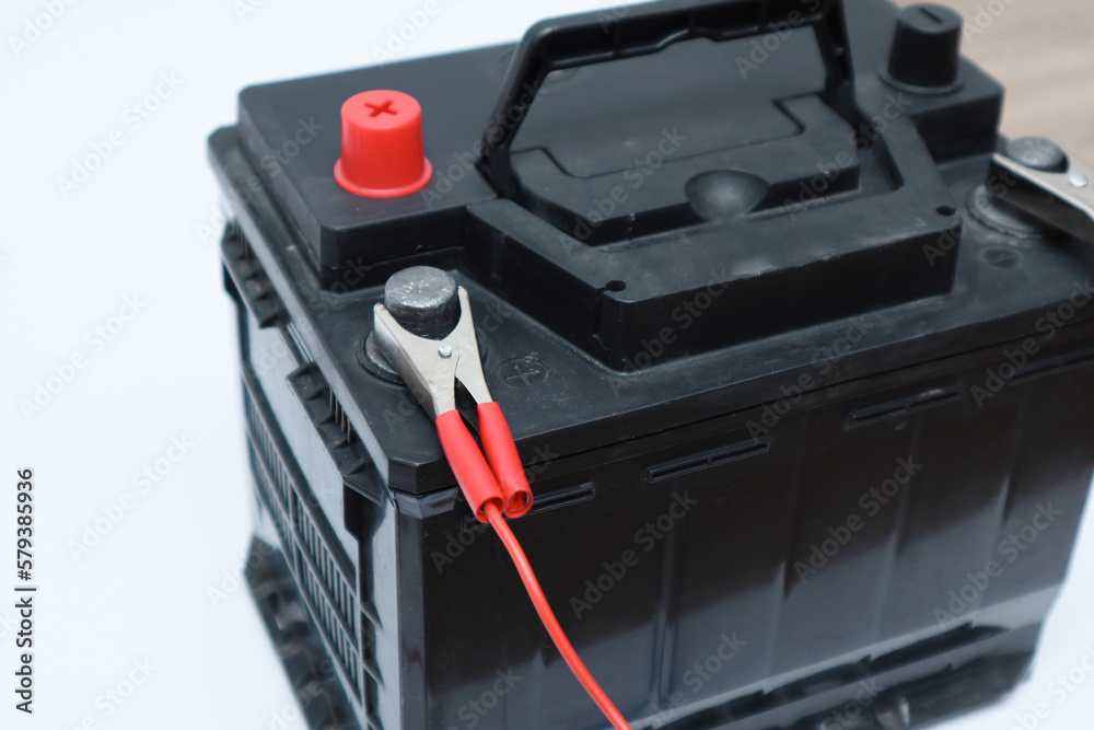Black car accumulator battery on a white background. Acid battery,12 volts supply. Concept of service, maintenance, charging car battery Black car accumulator battery on a white background. Acid battery,12 volts supply. Concept of service, maintenance, charging car battery