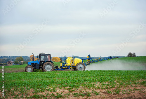 Tractor with mounted sprayer, farmer crop spraying. Tractor spraying pesticides on vegetable field with sprayer. Agricultural tractor spraying field. Tractor fertilize field pesticide and insecticide