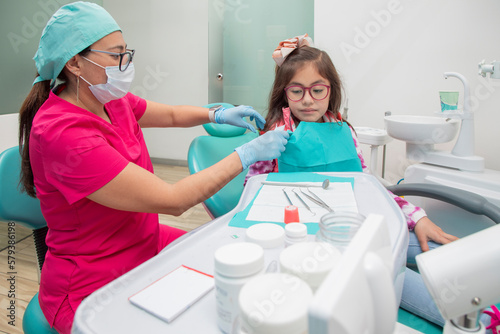 Female dentist with a young girl in her office after dental treatment