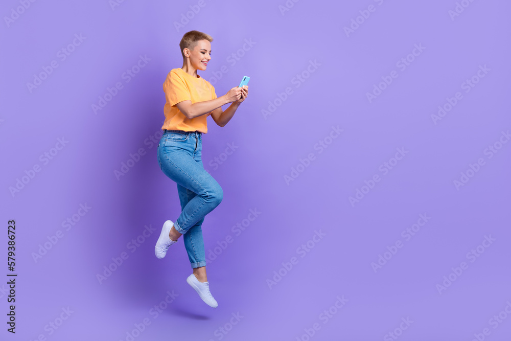 Full body profile portrait of carefree energetic lady jump use smart phone empty space isolated on purple color background