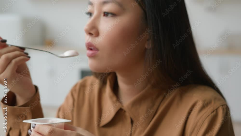 Close up view Asiana korean woman eat breakfast yogurt with spoon at home kitchen japanese girl eating ice cream lactose milk healthy nutrition low calories fruity dessert healthful food weight diet