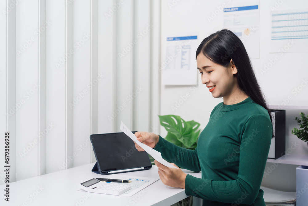 Young Asian household woman busy with bills and taxation, using calculator, make payment on tablet of family budget. Young Asian household woman busy with bills and taxation, using calculator, make payment on tablet of family budget.