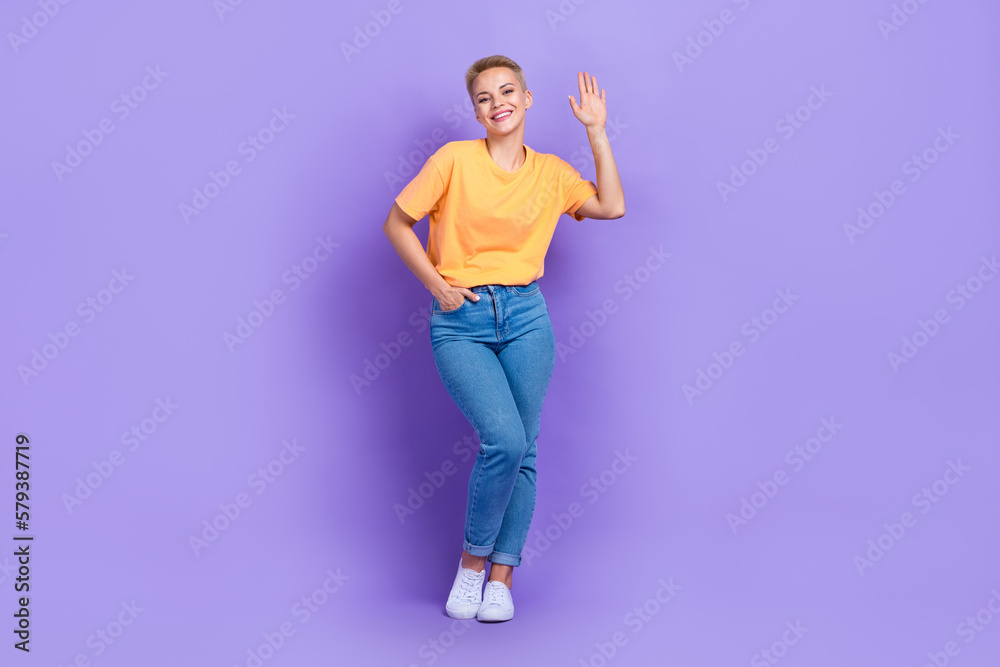 Full length photo of pleasant gorgeous girl dressed jeans white sneakers weaving palm greetings say hi isolated on violet color background Full length photo of pleasant gorgeous girl dressed jeans white sneakers weaving palm greetings say hi isolated on violet color background