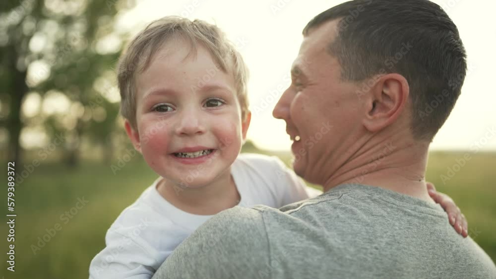 Happy family. Father and son are playing in the park. Baby in the arms of his father. Cheerful baby boy with father walk outdoors in the park. A smile on a child's face. Family team outdoors in park Happy family. Father and son are playing in the park. Baby in the arms of his father. Cheerful baby boy with father walk outdoors in the park. A smile on a child's face. Family team outdoors in park