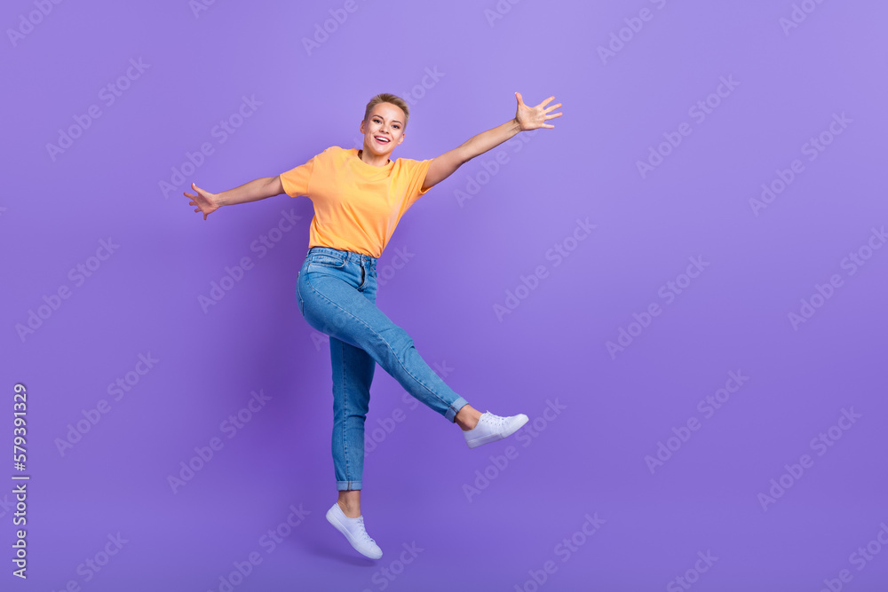 Full length photo of pleasant friendly nice girl jeans white sneakers flying jumping having fun isolated on violet color background