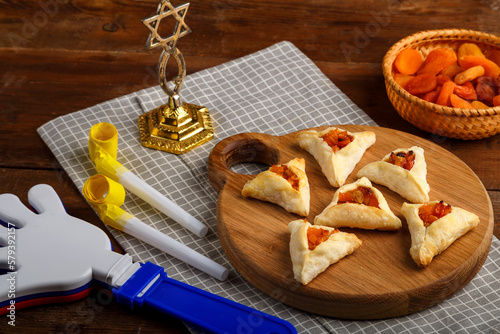 gometashi triangles cookies with mishloach manot jam for Purim laid out on a wooden board on a napkin next to the menorah rattle and whistle.