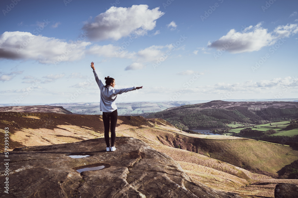 Woman standing on top of the mountain, admiring the view, Peak District National Park Woman standing on top of the mountain, admiring the view, Peak District National Park