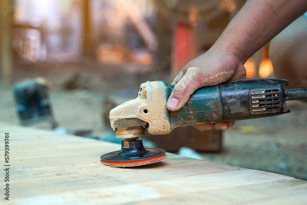 Carpenters use a sander to sand the surface of the wood to smooth the woodwork before painting. Soft and selective focus.