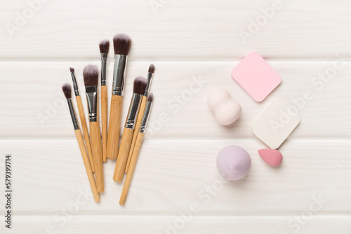 Make up brush and sponge on wooden background, top view