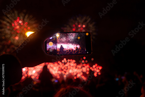 Hand of man taking the photo of fireworks by smartphone