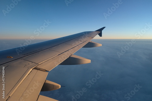 Beautiful shot of a plane wing over a layer of blue clouds
