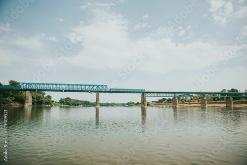 View of a fenced old bridge over the wide river on a sunny day