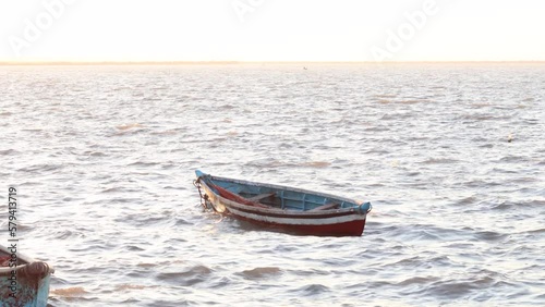 fisherman's empty boat in shore, on board a small and characteristic fishing boat in diu and daman. small solitary vessel, moored or anchored, on a calm half light and half dark sea or lake surface photo
